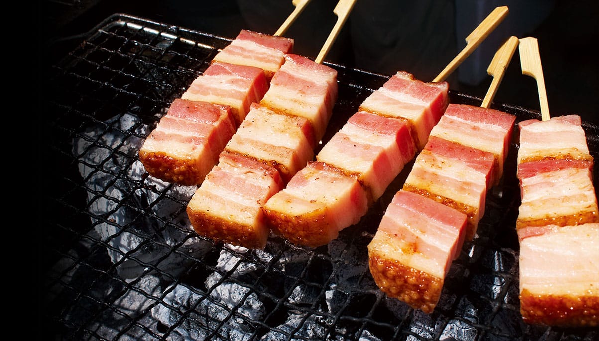 炭火で炙るベーコンの串焼き