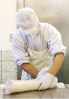 ロースハムを布で手巻きする職人